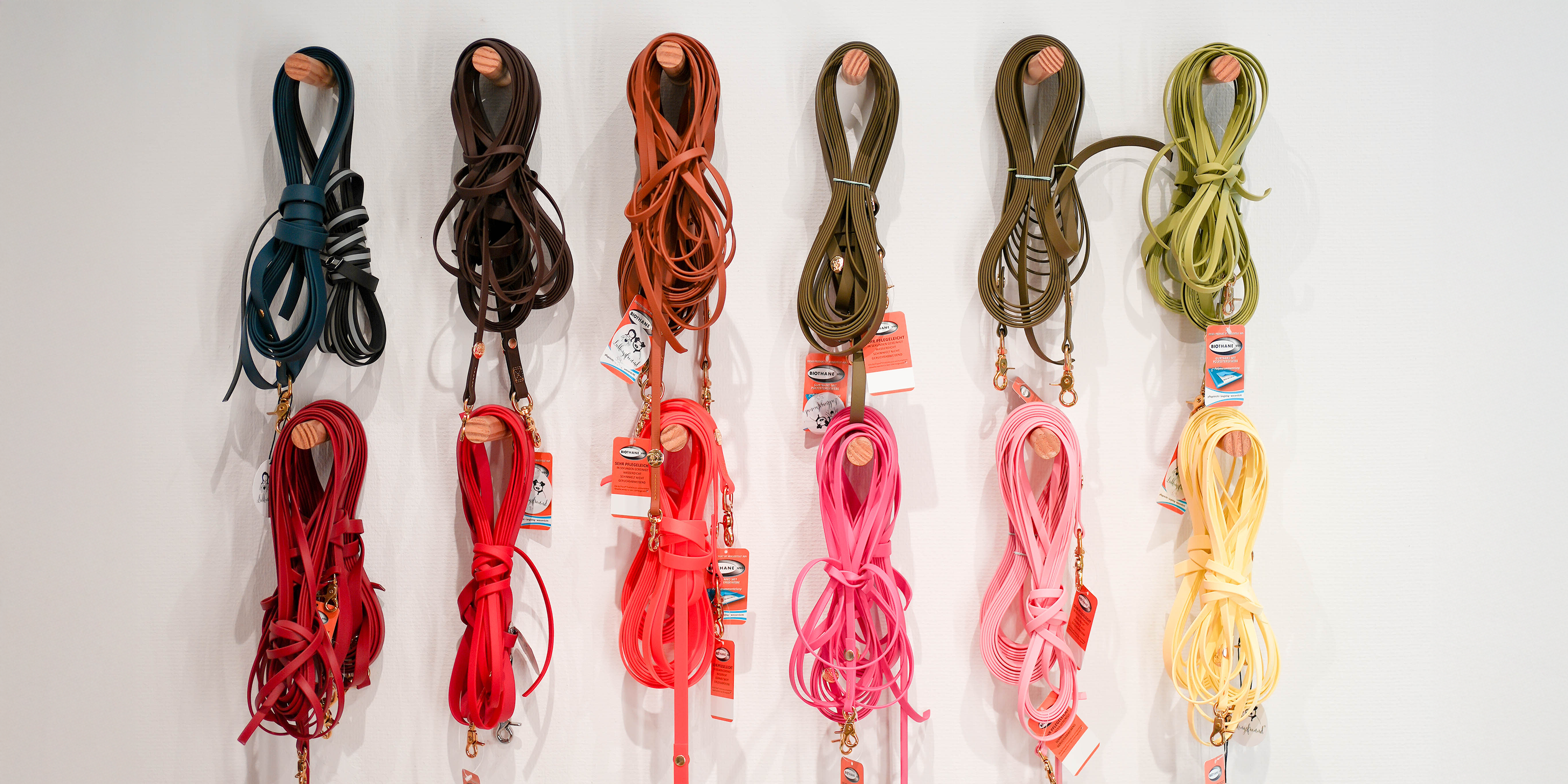 Farbenfrohe Schleppleinen für Hunde in Blau, Braun, Rot, Pink, Grün und Gelb, ordentlich nebeneinander in der Lieblingsfreund Boutique aufgehängt.